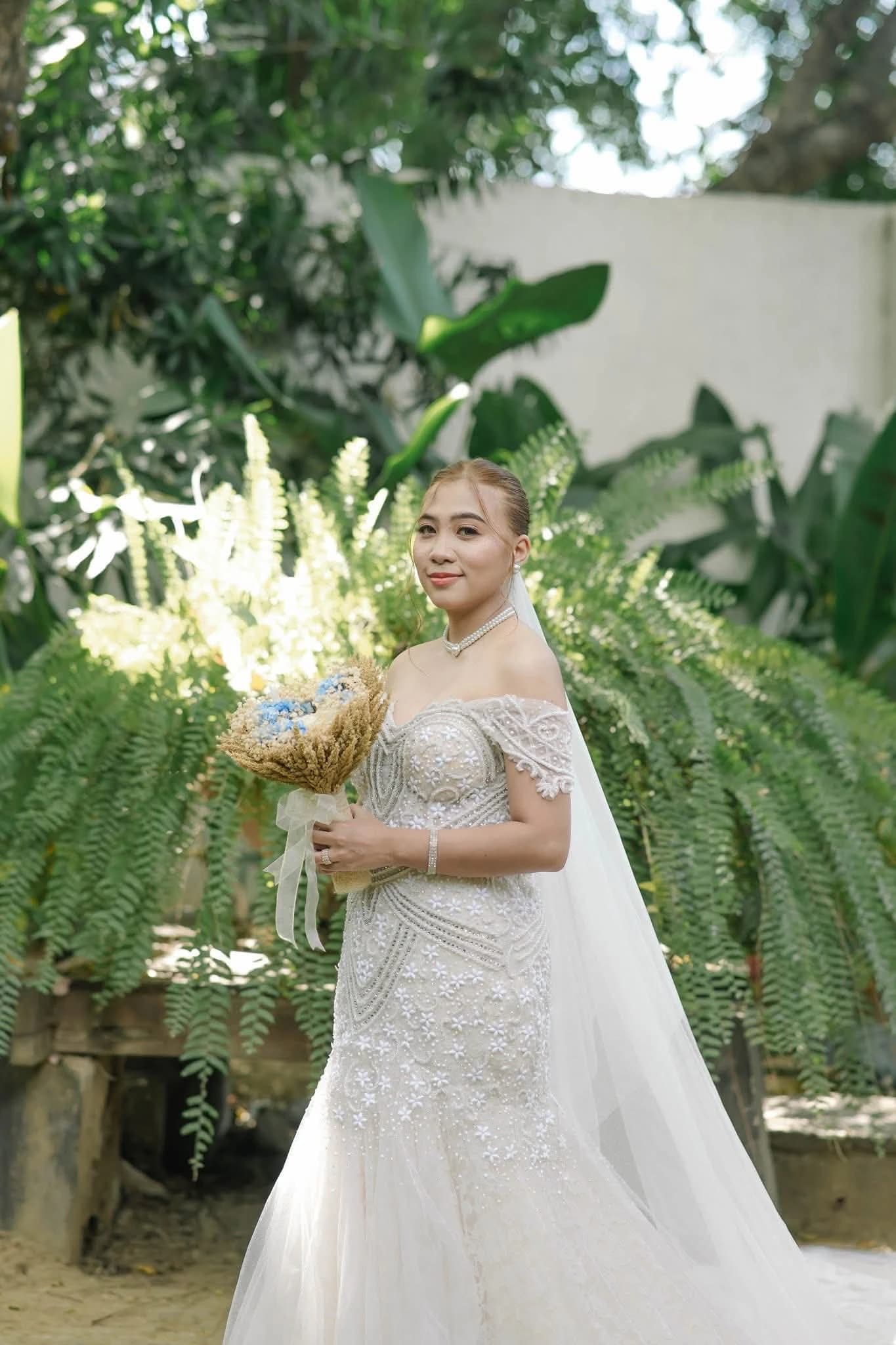 Bride beneath a fern arch holding a dried bouquet
