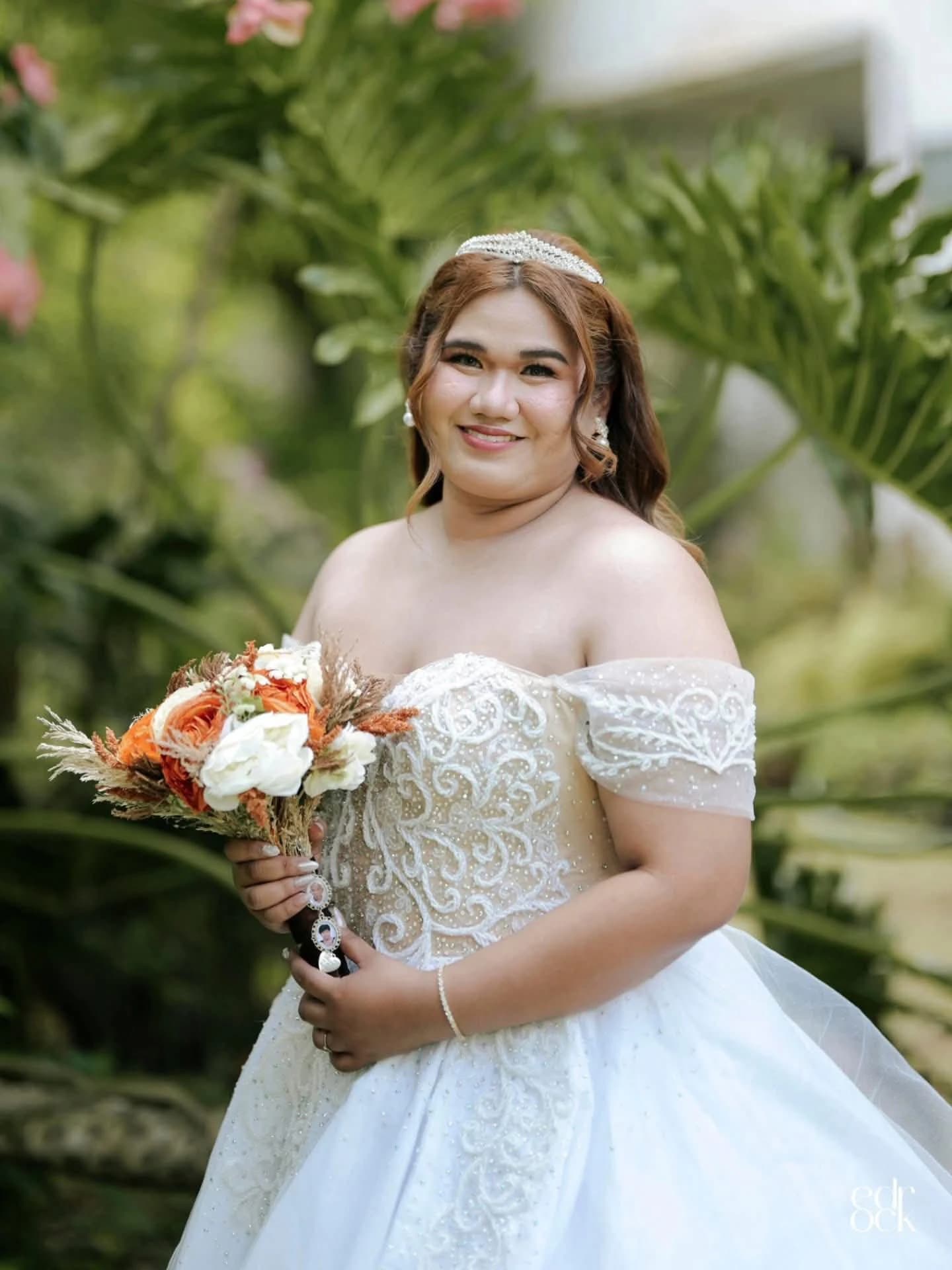 Bride holding an orange bouquet in a green garden