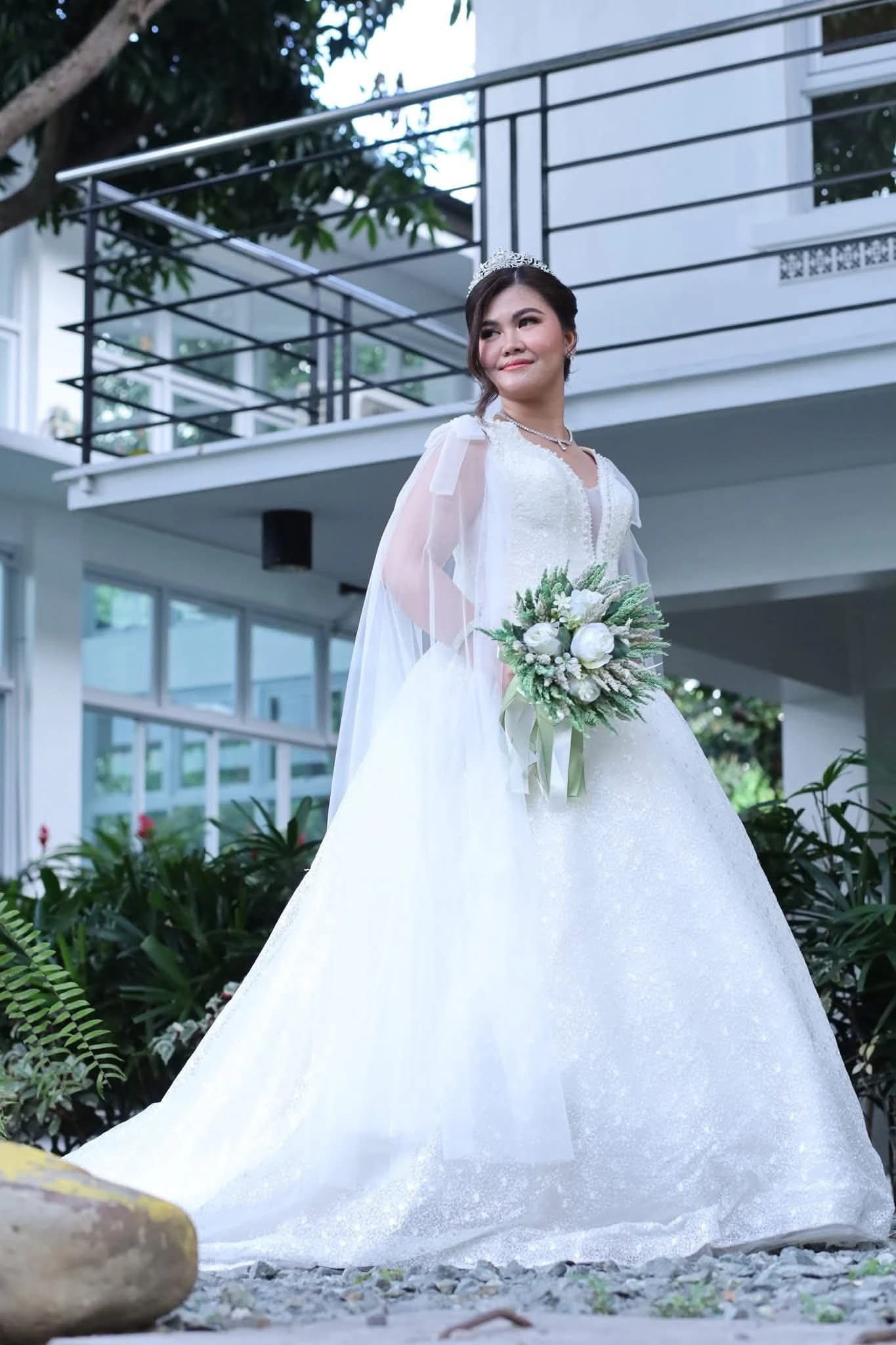 Bride in a white gown holding a bouquet outdoors