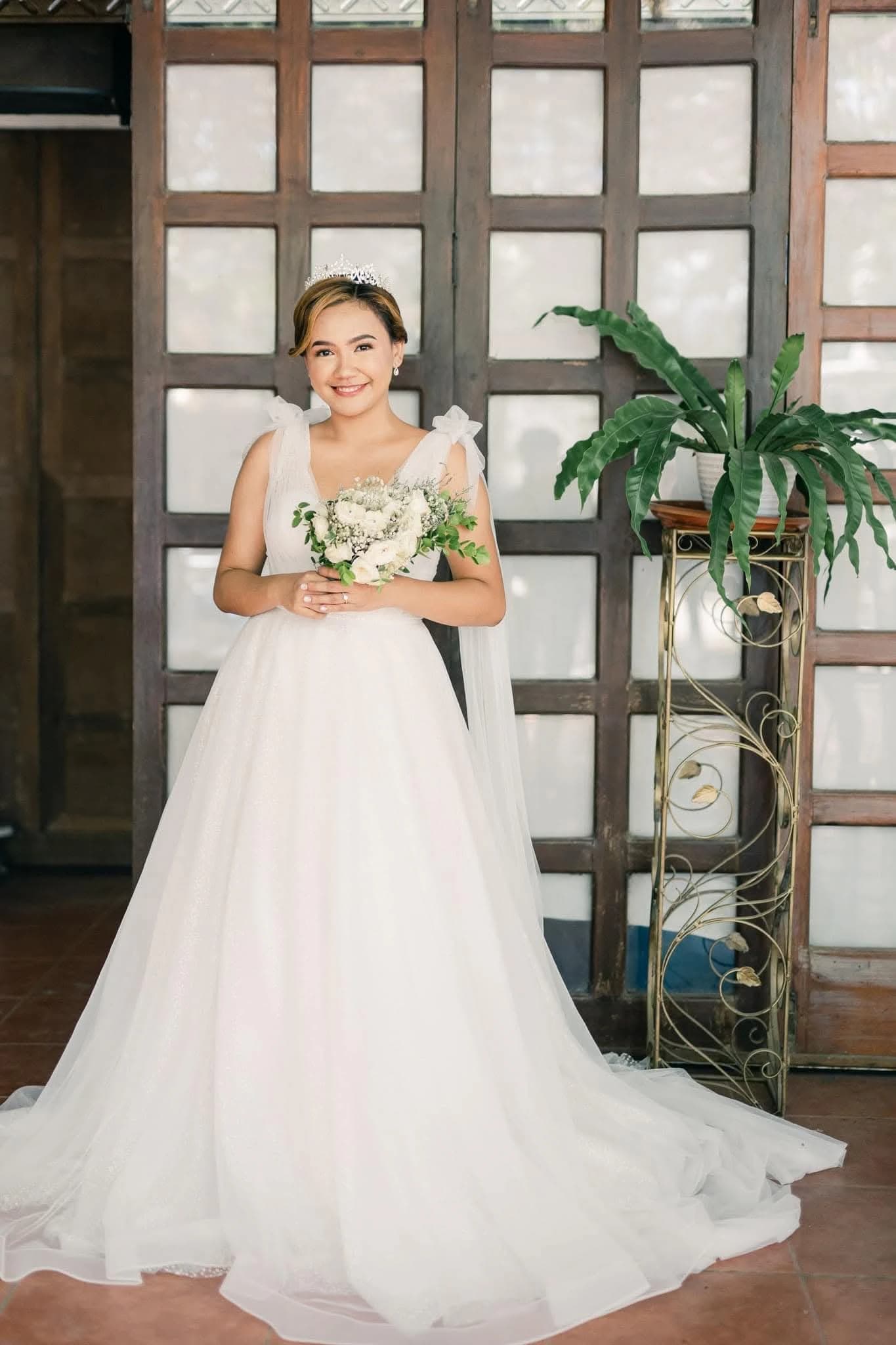 Bride in a pale pink gown posing in a wooden doorway
