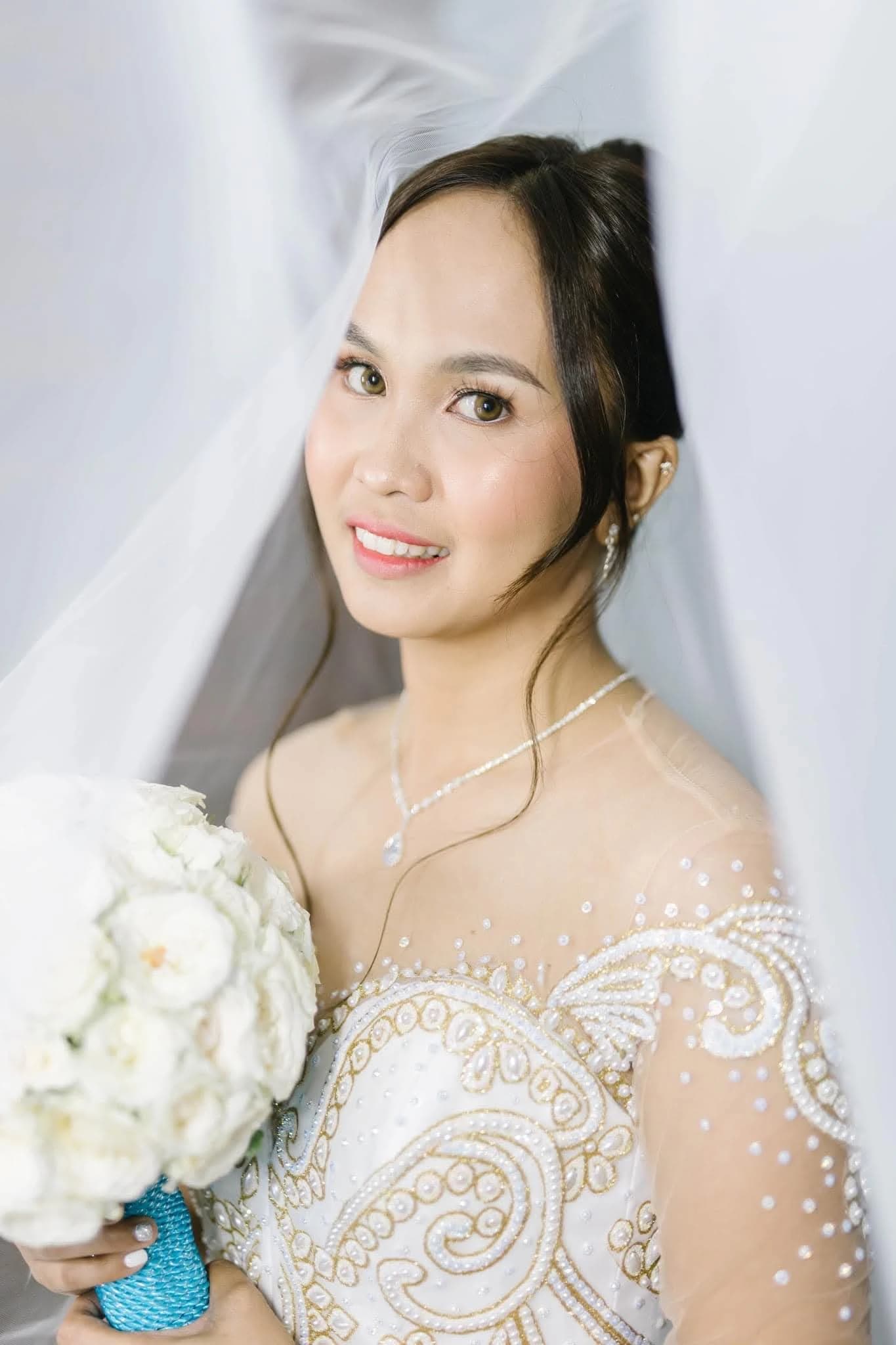 Close-up bridal portrait with veil, beaded gown and white bouquet