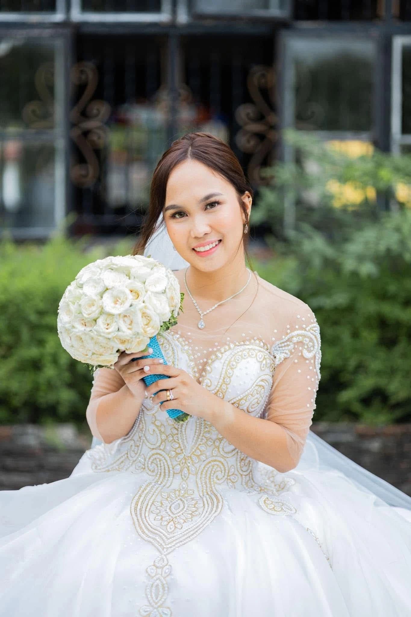 Bride in a beaded gown holding white roses outdoors