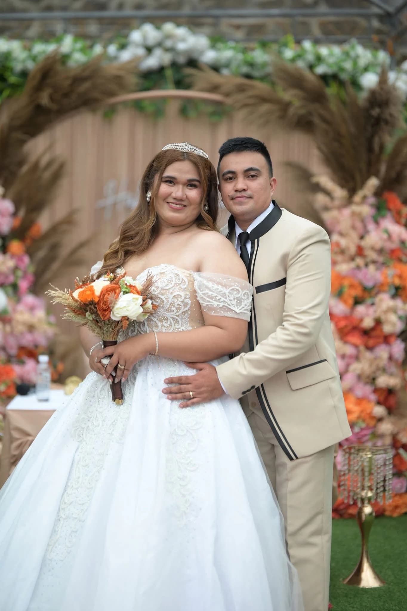 Wedding couple posing before a warm floral backdrop